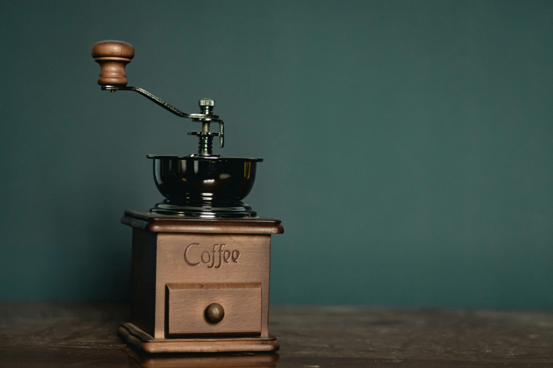 Klassieke handkoffiemolen voor een groene muur