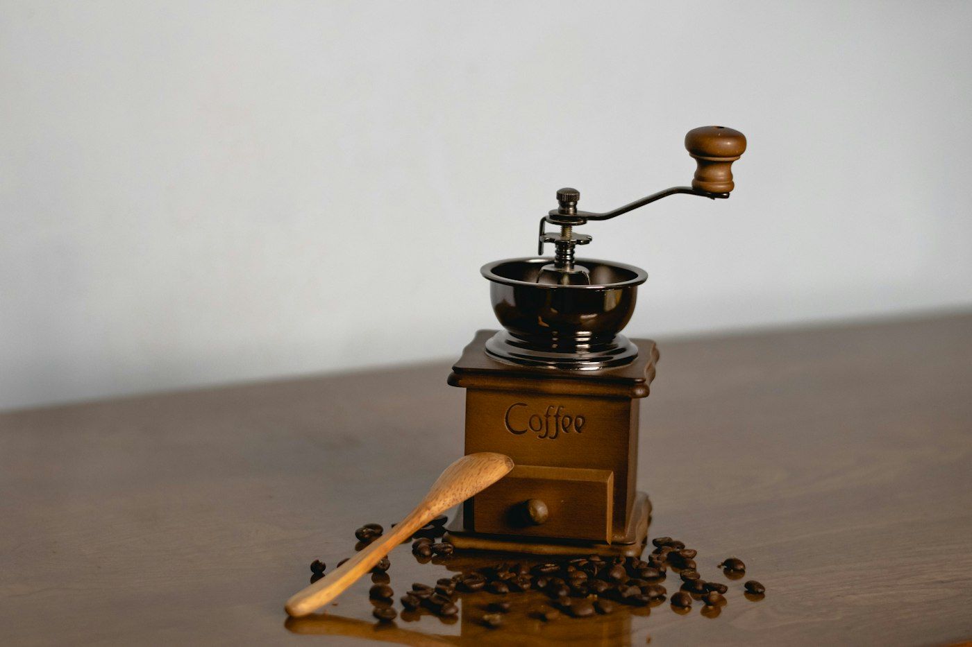 Houten handkoffiemolen met bonen op tafel
