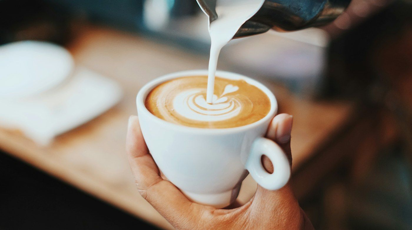 Melk wordt in een cappuccino geschonken voor latte art